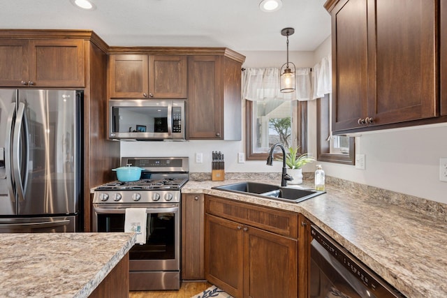 kitchen featuring decorative light fixtures, recessed lighting, appliances with stainless steel finishes, and a sink