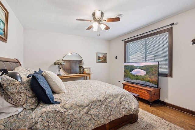 bedroom with ceiling fan, baseboards, and wood finished floors