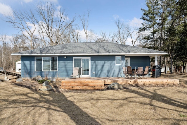 rear view of property featuring a patio and a shingled roof