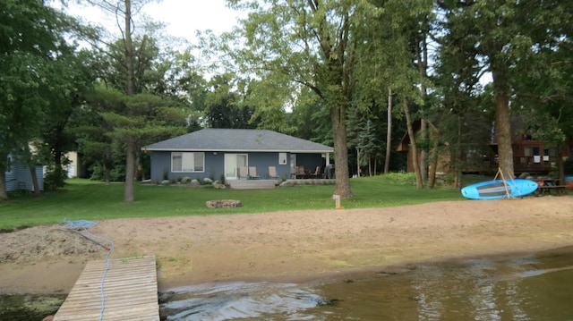 back of house with a water view and a lawn