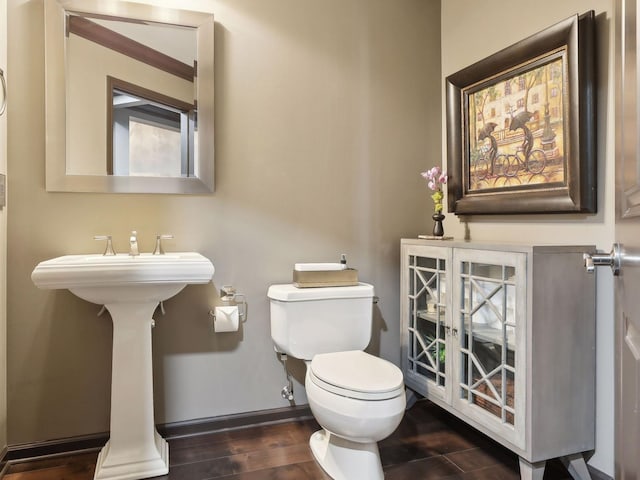 half bath featuring baseboards, toilet, and wood finished floors