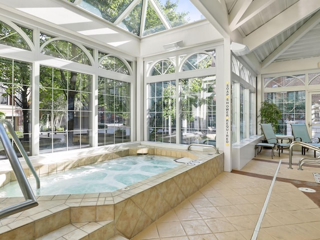 unfurnished sunroom featuring a jacuzzi, beam ceiling, and a skylight