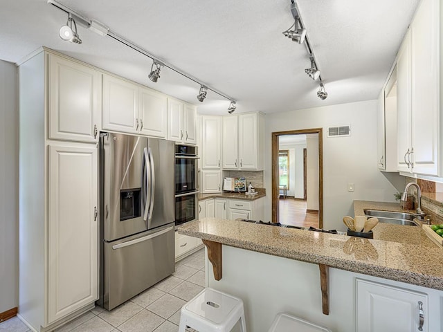 5109 Richmond Dr, Edina, MN 55436 - kitchen with stainless steel appliances, a peninsula, rail lighting, and backsplash