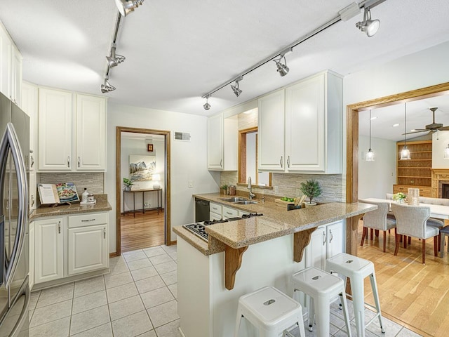 5109 Richmond Dr, Edina, MN 55436 - kitchen with a sink, a kitchen bar, freestanding refrigerator, rail lighting, and tasteful backsplash