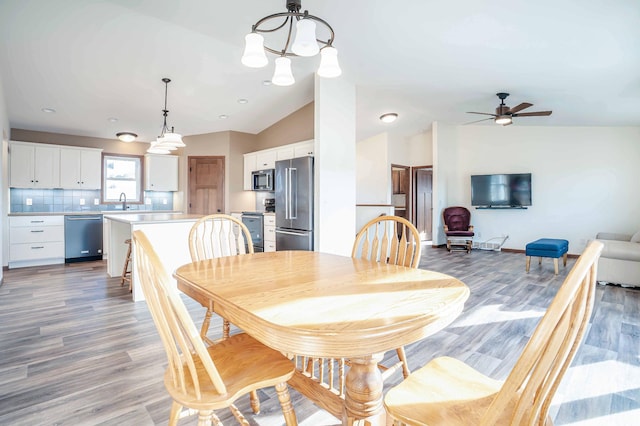 dining room with baseboards, light wood-type flooring, a ceiling fan, and vaulted ceiling