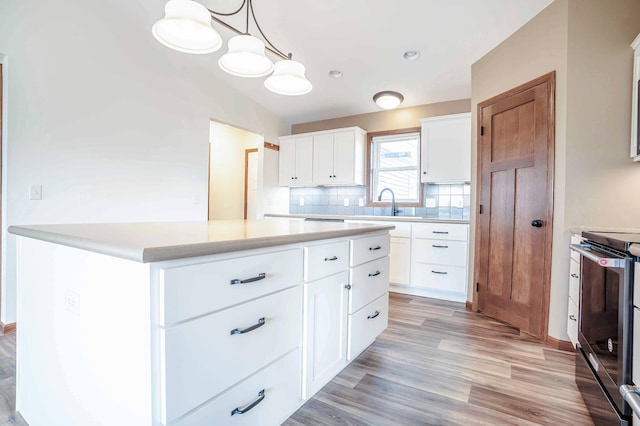 kitchen featuring a kitchen island, stainless steel range with electric cooktop, light countertops, light wood-style floors, and backsplash