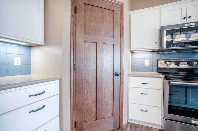 kitchen featuring tasteful backsplash, appliances with stainless steel finishes, white cabinetry, and light countertops