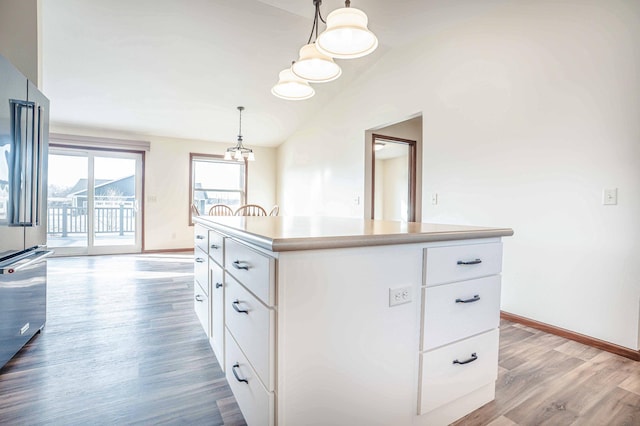 kitchen with lofted ceiling, high quality fridge, wood finished floors, and white cabinetry