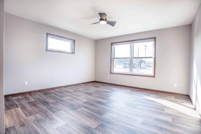 spare room with baseboards, wood finished floors, and a ceiling fan