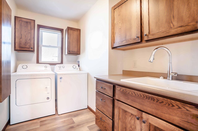 laundry area with a sink, cabinet space, separate washer and dryer, and light wood finished floors