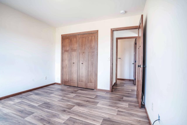 unfurnished bedroom featuring a closet, baseboards, and light wood-style flooring