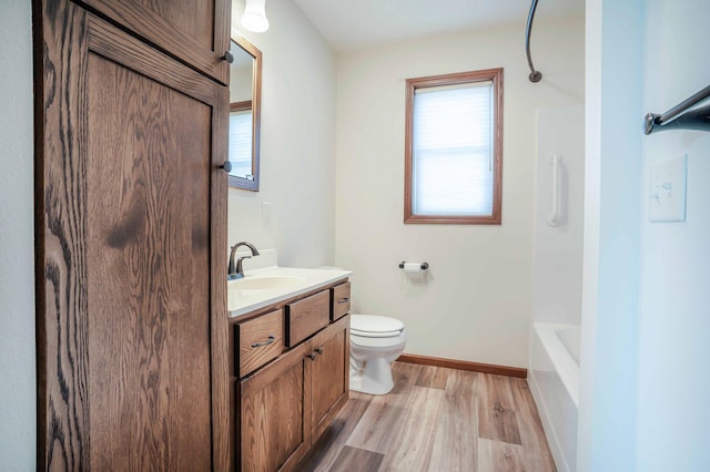 bathroom with tub / shower combination, baseboards, toilet, wood finished floors, and vanity