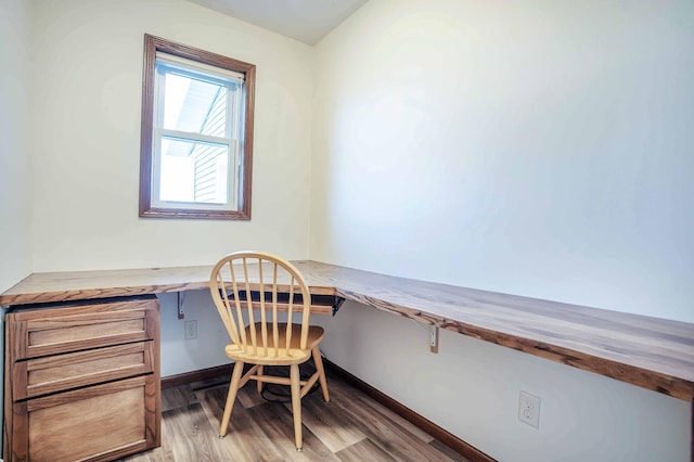 office area with light wood-style floors and built in study area