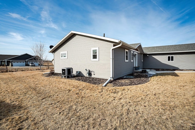 back of house featuring central air condition unit and a lawn