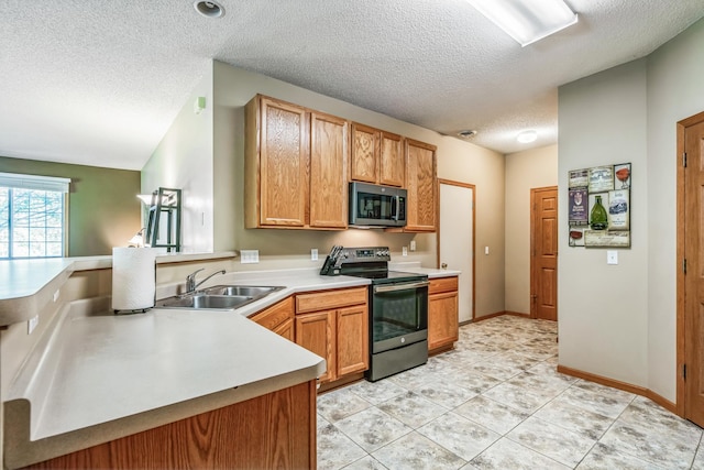 kitchen with a sink, a textured ceiling, appliances with stainless steel finishes, a peninsula, and light countertops