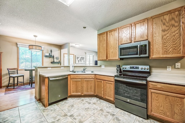 kitchen featuring light countertops, light tile patterned floors, a peninsula, stainless steel appliances, and a sink