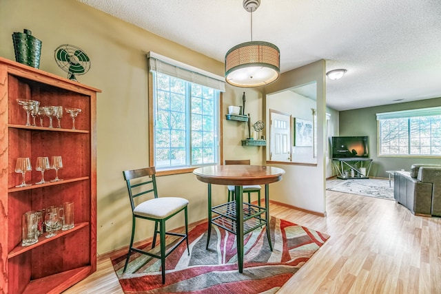 dining space featuring baseboards, a textured ceiling, and wood finished floors