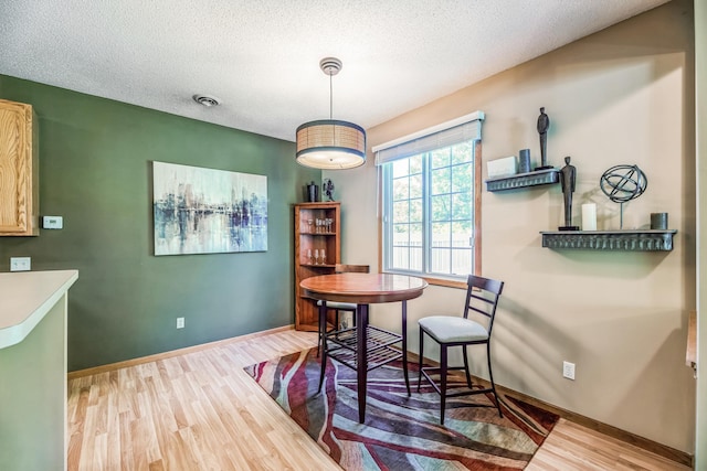 dining room featuring visible vents, baseboards, a textured ceiling, and wood finished floors