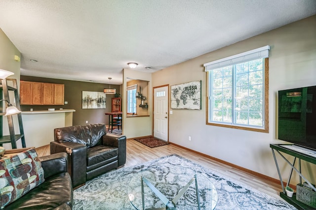 living room with baseboards, a textured ceiling, and light wood-style flooring