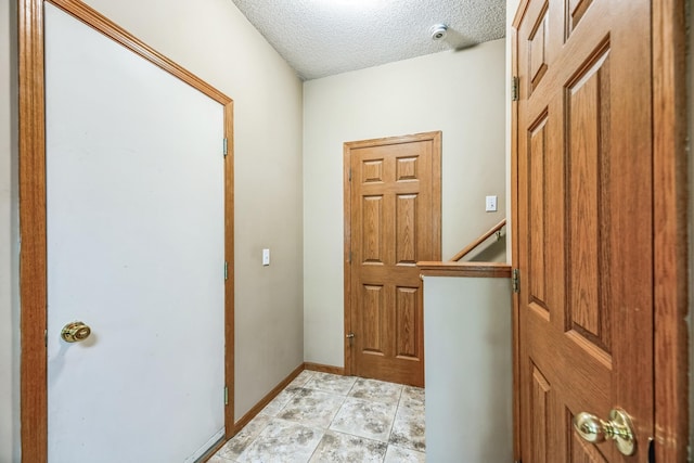 interior space with baseboards, a textured ceiling, and an upstairs landing