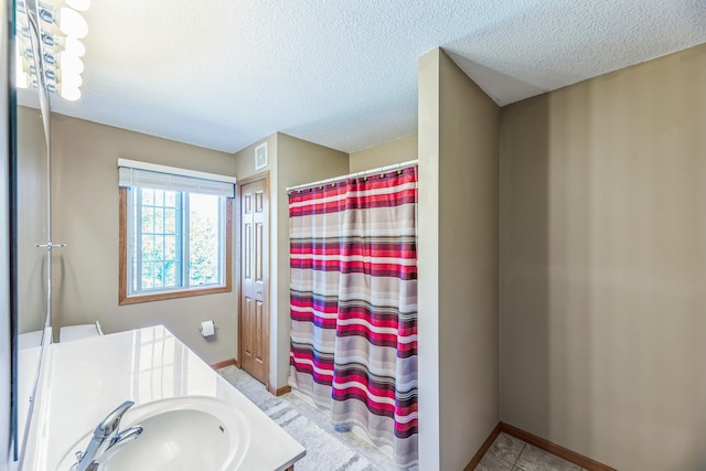 bathroom featuring a shower with curtain, a textured ceiling, vanity, and baseboards