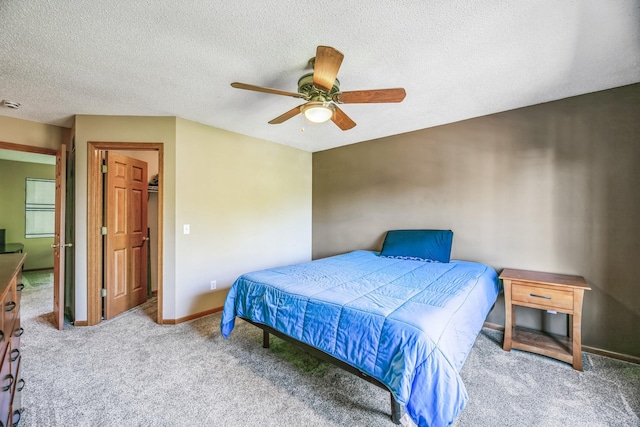 carpeted bedroom featuring a textured ceiling, a ceiling fan, and baseboards