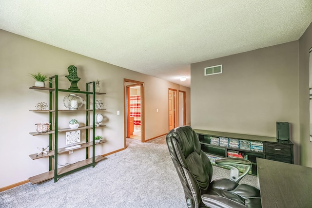 office area with visible vents, carpet floors, a textured ceiling, and baseboards