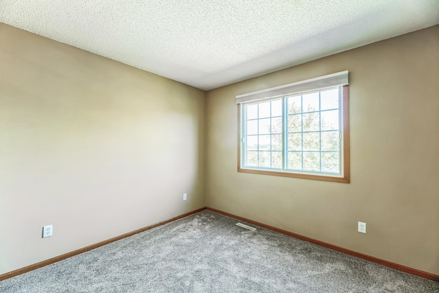 spare room featuring visible vents, carpet floors, a textured ceiling, and baseboards