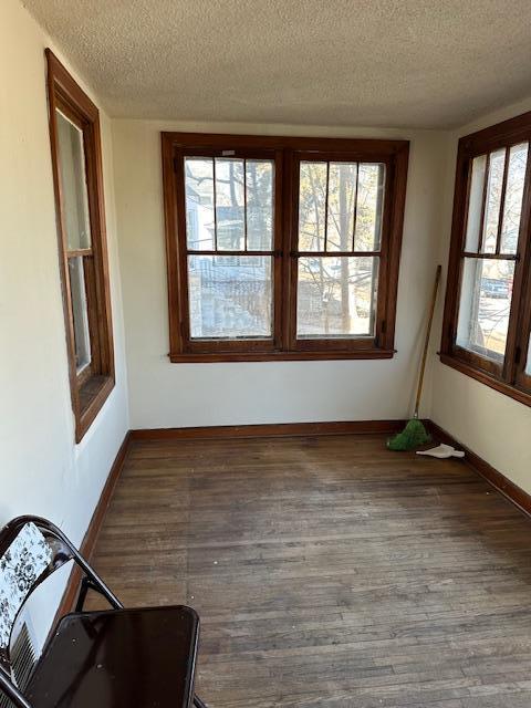 interior space featuring a textured ceiling, baseboards, and wood finished floors