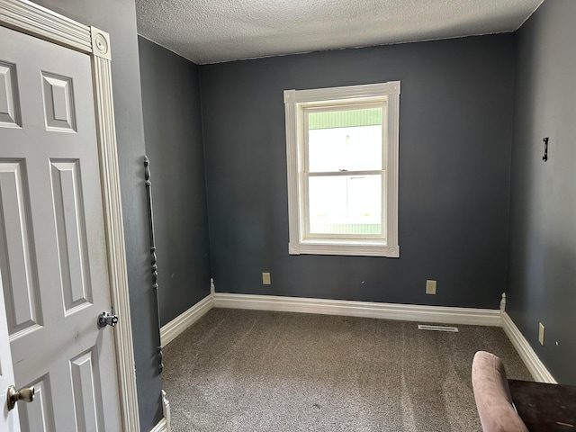 empty room with visible vents, baseboards, carpet, and a textured ceiling