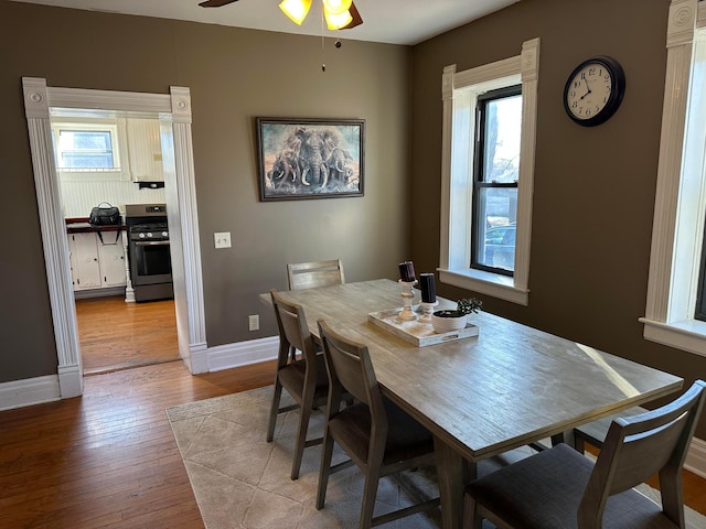 dining room featuring baseboards, light wood-style floors, a healthy amount of sunlight, and a ceiling fan