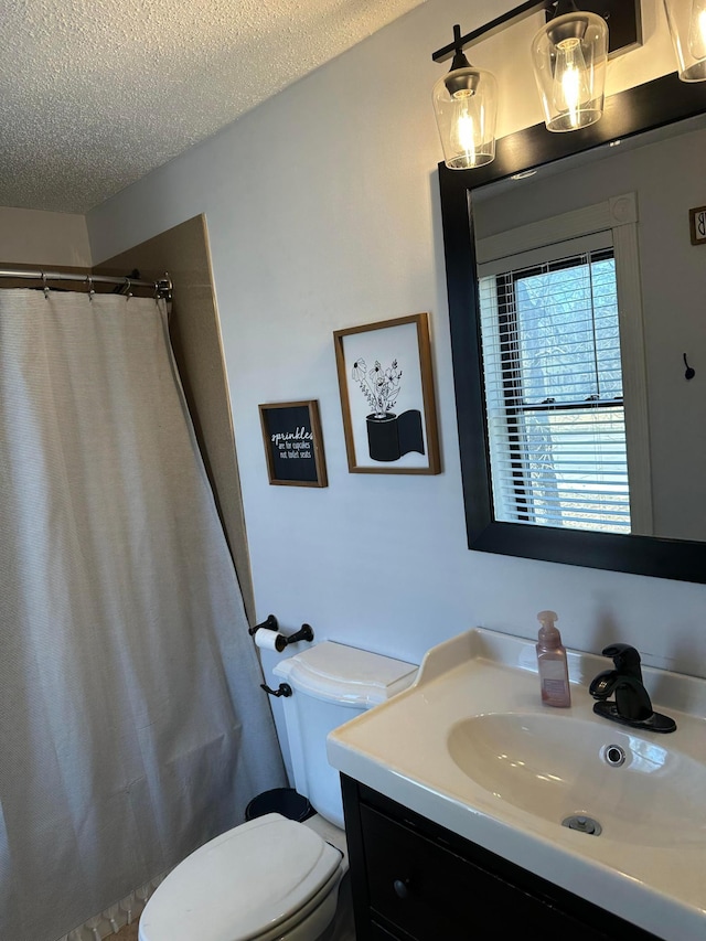 full bath featuring curtained shower, a textured ceiling, vanity, and toilet