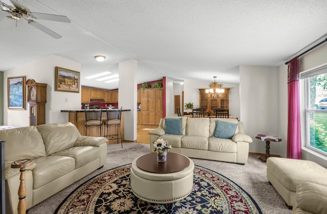 living room with light carpet, ceiling fan with notable chandelier, a textured ceiling, and lofted ceiling