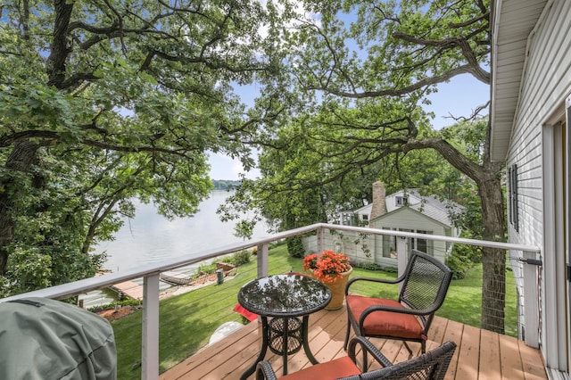 deck featuring a yard, a water view, and a grill