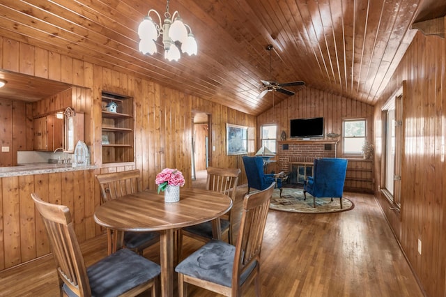 dining space featuring wood-type flooring, wood walls, wooden ceiling, a fireplace, and vaulted ceiling