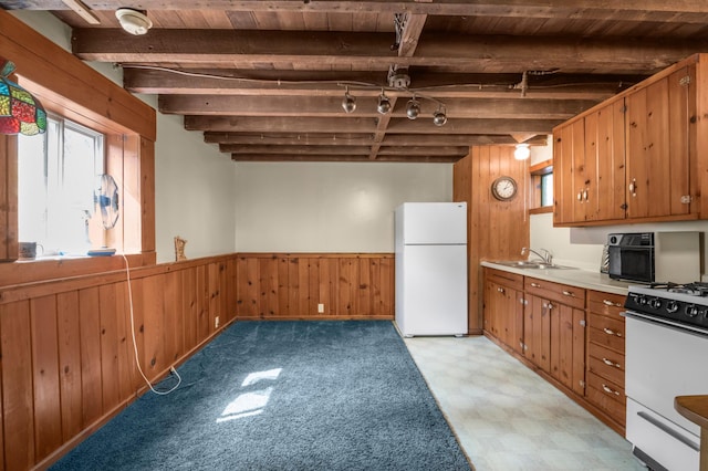 kitchen with beamed ceiling, light floors, white appliances, and wood walls