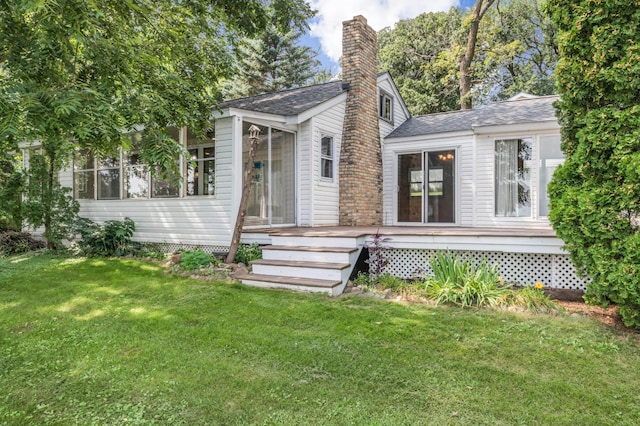 view of front of house featuring a deck, a front lawn, a sunroom, and a chimney