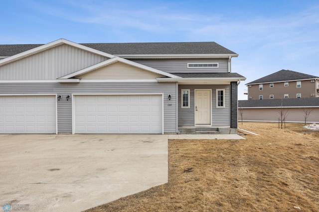 view of front facade with an attached garage, roof with shingles, and driveway