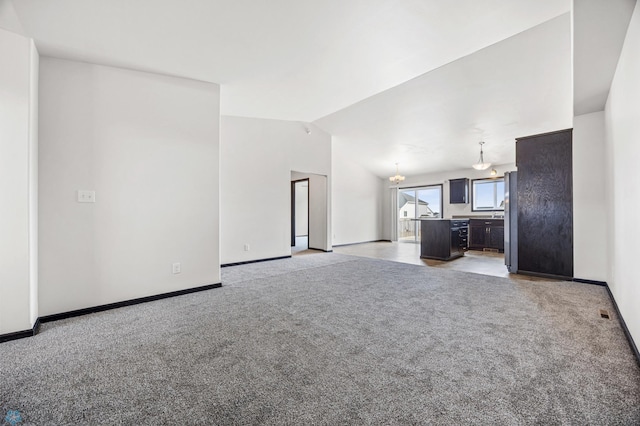 unfurnished living room featuring baseboards, lofted ceiling, and light colored carpet