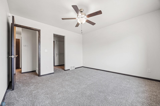 unfurnished bedroom with visible vents, baseboards, a walk in closet, and carpet flooring