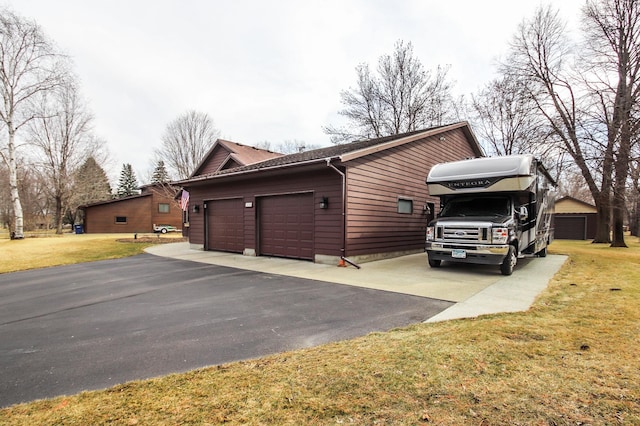 view of side of home featuring an attached garage, a yard, and driveway