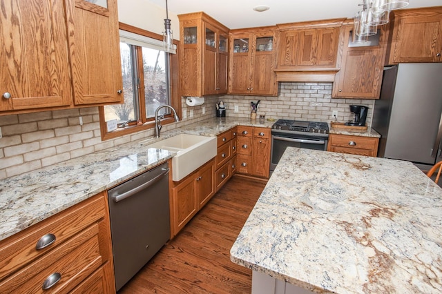 kitchen featuring brown cabinets, dark wood-style flooring, appliances with stainless steel finishes, and a sink