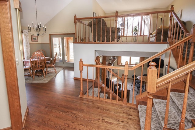 staircase featuring high vaulted ceiling, wood finished floors, and a chandelier