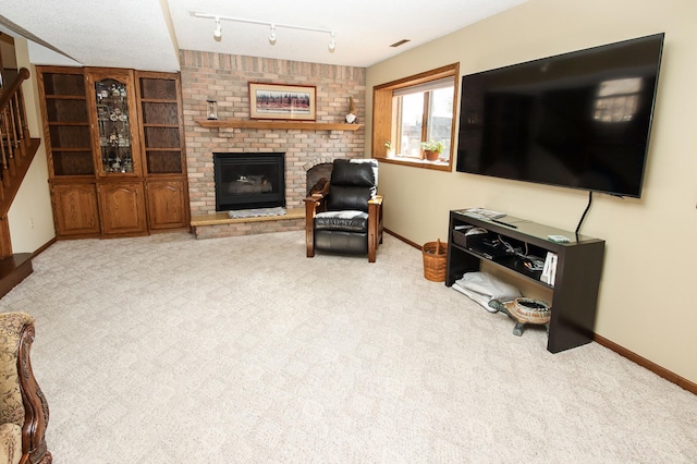 carpeted living room featuring stairway, a fireplace, track lighting, and baseboards