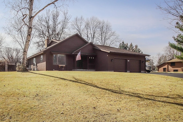 view of front facade featuring an attached garage, a chimney, driveway, and a front lawn