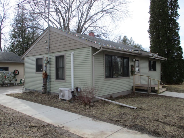 bungalow-style home with ac unit and a chimney