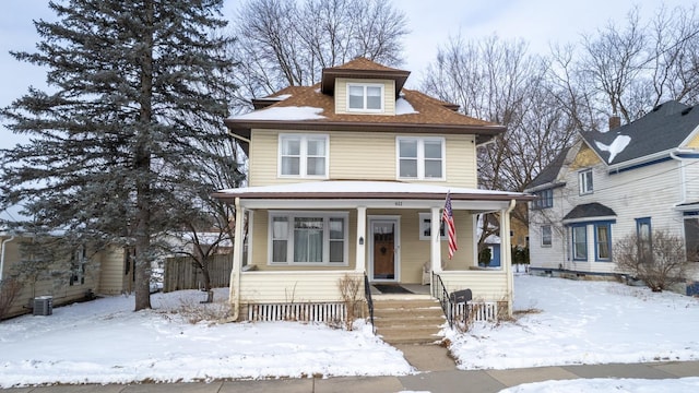 american foursquare style home with central air condition unit and covered porch