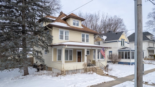 american foursquare style home with fence, a porch, central AC, a chimney, and a sunroom