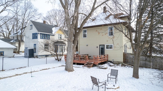 snow covered property with a deck and fence