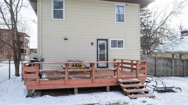 snow covered property featuring a wooden deck and fence